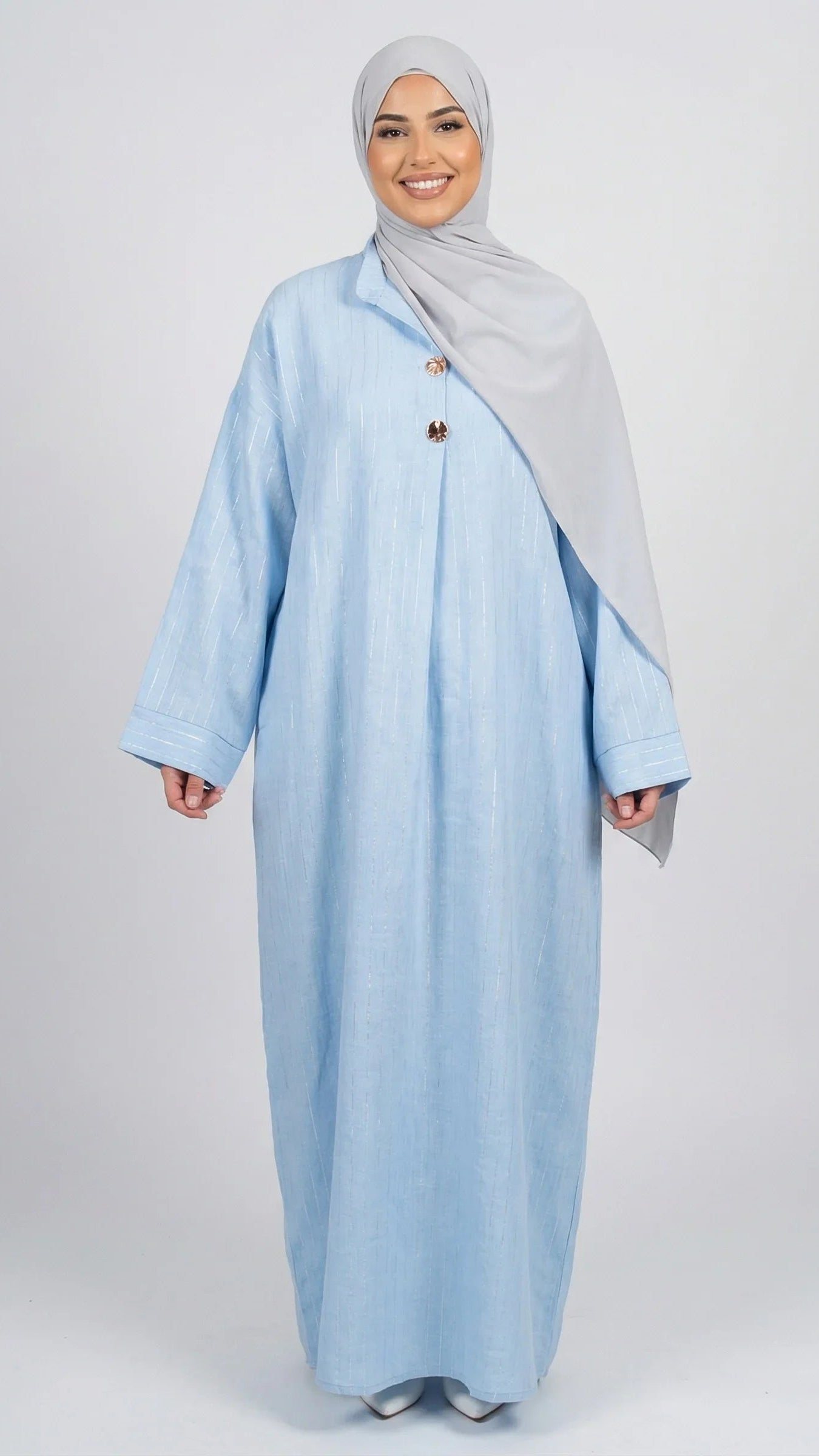 Femme souriante portant abaya bleu clair et hijab gris, mode modeste moderne Muneera