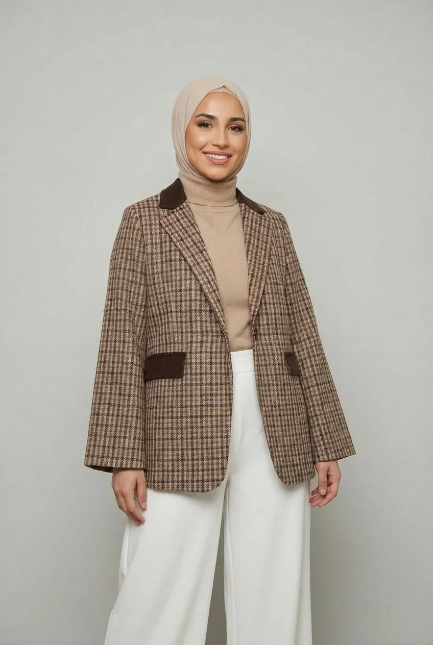 Femme souriante en blazer à carreaux Muneera, hijab beige et pantalon large blanc, mode modeste élégante.