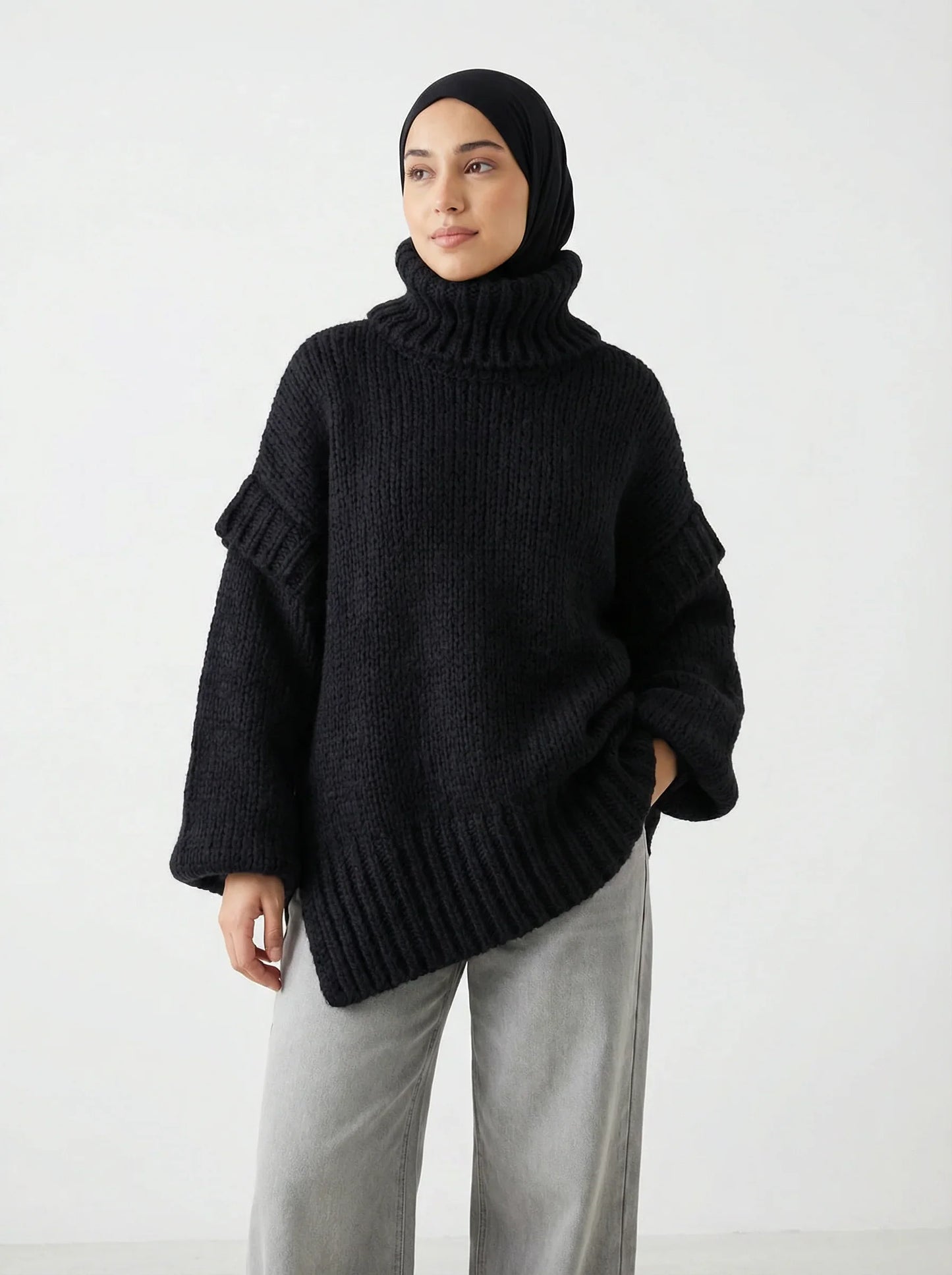 Femme portant un pull noir en maille épaisse Muneera, style mode modeste élégant.