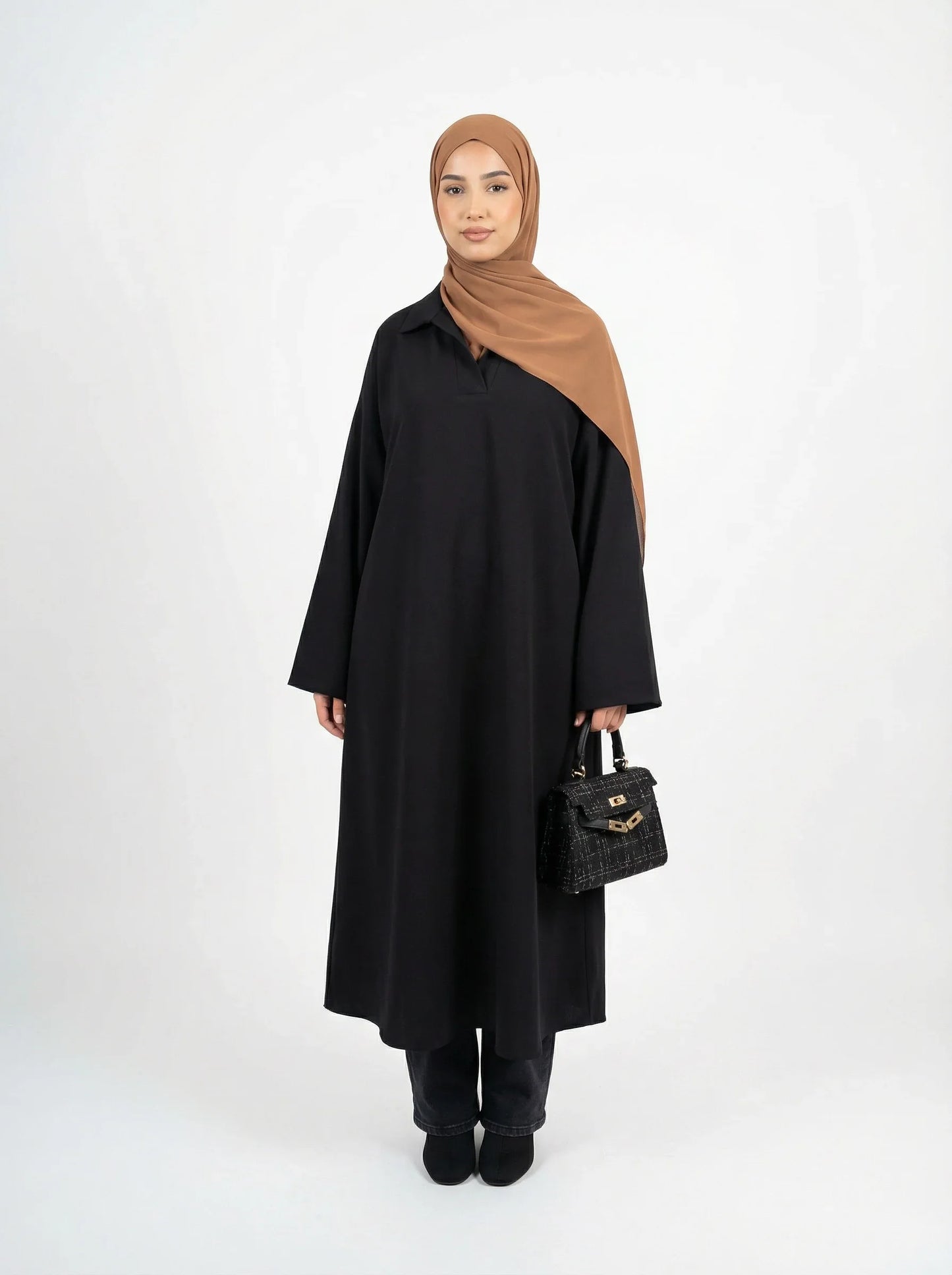 Femme en tenue Muneera élégante, abaya noire, hijab marron, sac à main noir, mode modeste