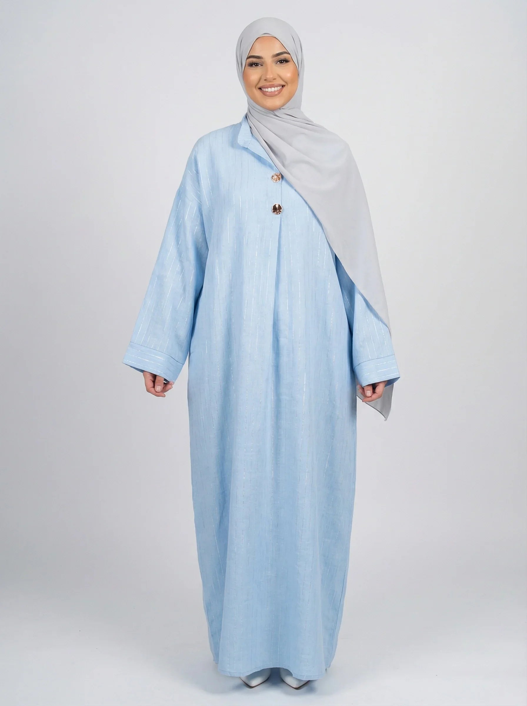 Femme souriante portant abaya bleu clair et hijab gris, mode modeste moderne Muneera