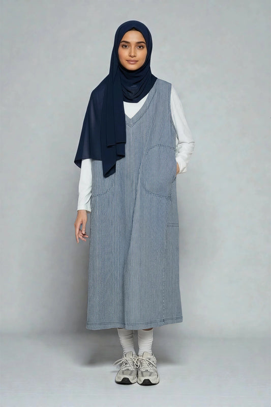 Femme portant une robe longue rayée bleu Muneera, hijab bleu marine et haut blanc, style mode modeste.