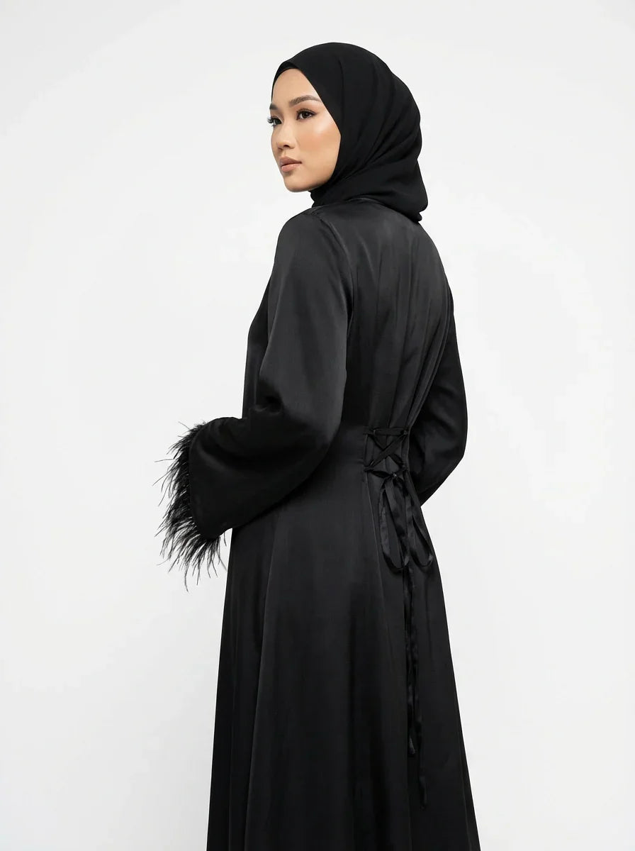 Femme portant une abaya noire élégante avec manches à plumes, mode modeste Muneera