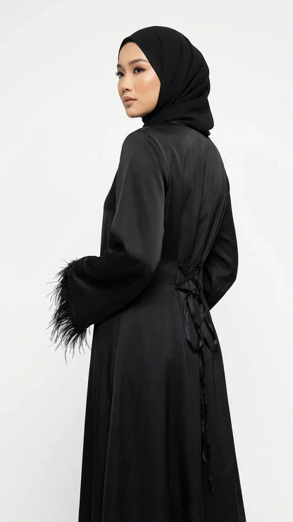 Femme portant une abaya noire élégante avec manches à plumes, mode modeste Muneera