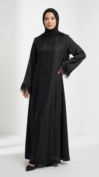Femme portant une abaya satinée noire élégante avec manches à plumes, mode modeste Muneera