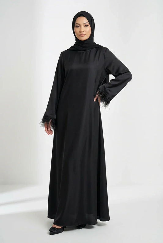 Femme portant une abaya satinée noire élégante avec manches à plumes, mode modeste Muneera
