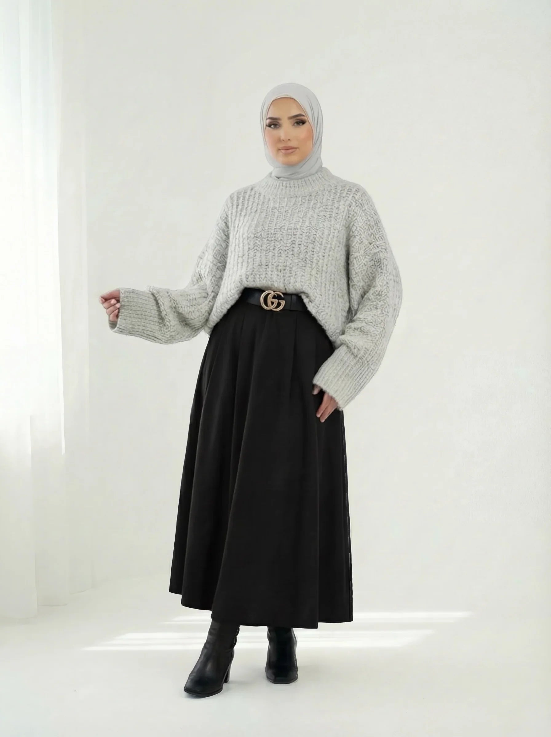 Femme portant un hijab gris, pull en maille et jupe noire longue, style mode modeste Muneera.