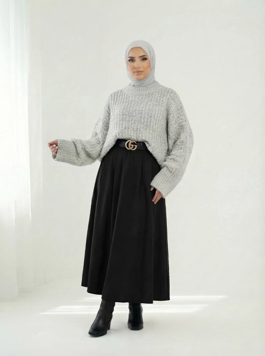 Femme portant un hijab gris, pull en maille et jupe noire longue, style mode modeste Muneera.